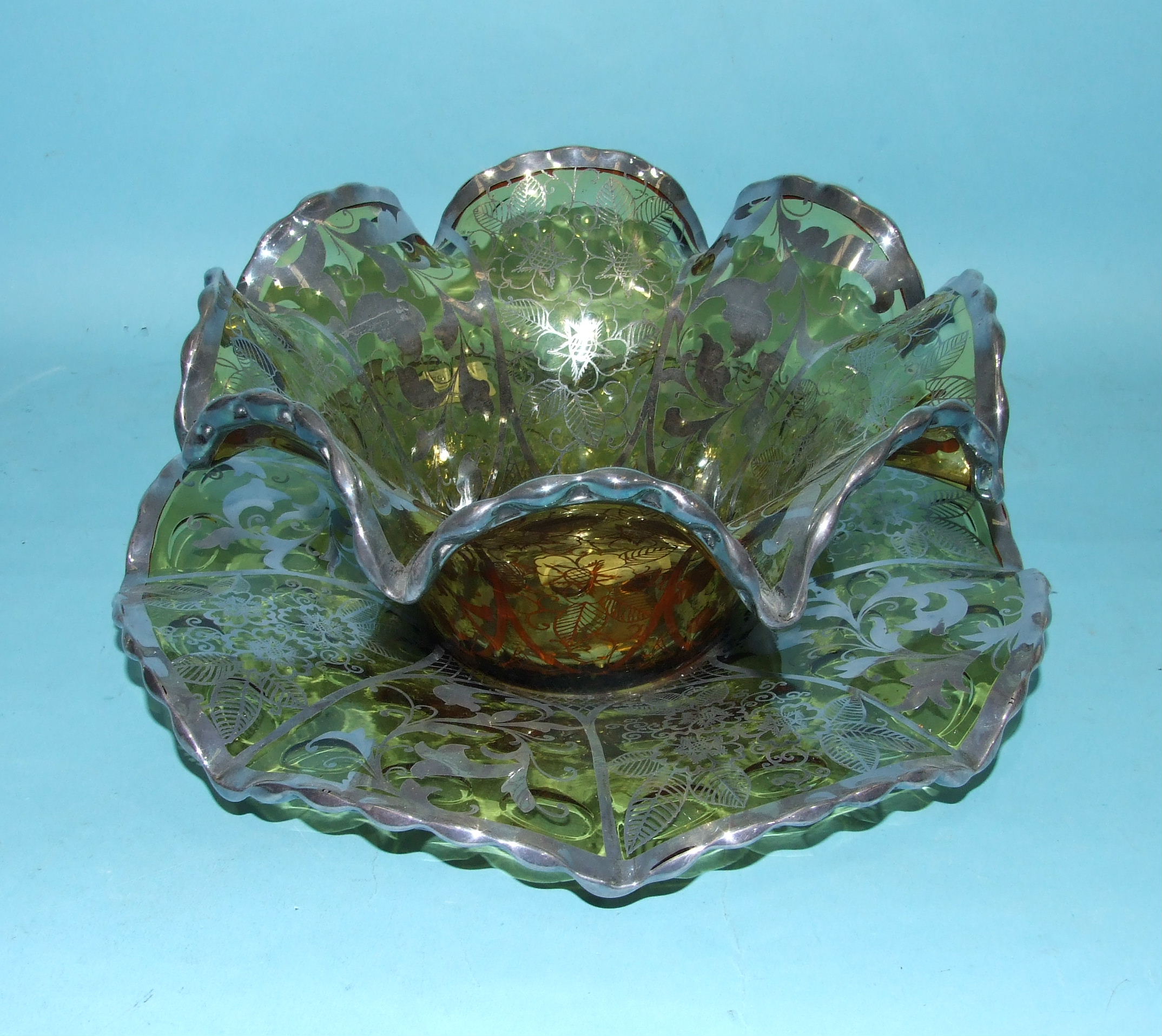 A Continental beige glass bowl on stand, of undulating wavy form with foliate silver metal overlay