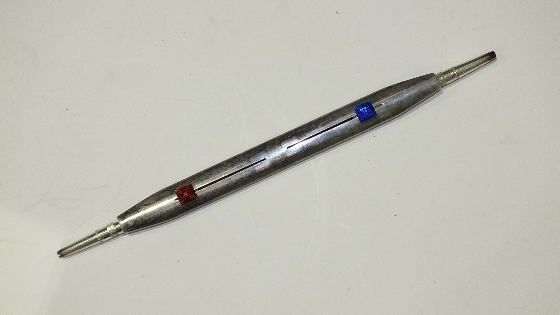 An Edwardian plated double-ended propelling pencil with blue and red enamelled thumb pieces, 18cm