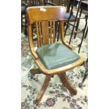 A 1920's/1930's oak revolving office chair with padded seat, on quadruped base.