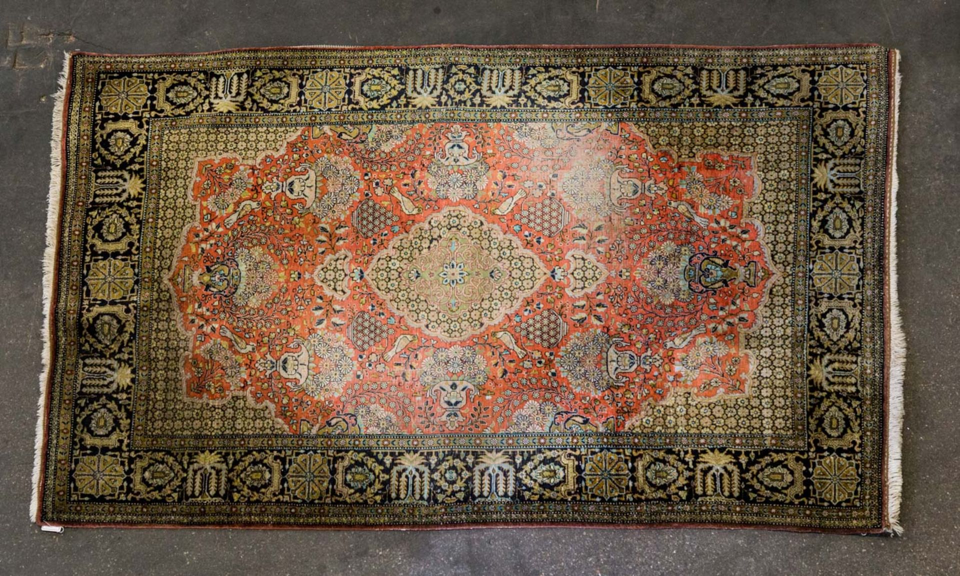 Orientteppich aus Seide. GHOM/PERSIEN, 20. Jh., 175x108 cm der orangerote Fond des Innenfeldes zeigt