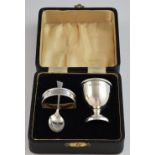 George V silver three piece christening set, comprising egg cup (base loaded), spoon and napkin