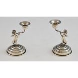 Pair of continental silver candlesticks on the form of cherubs blowing horns, on round feet,