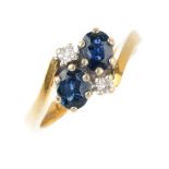 An 18ct gold sapphire and diamond dress ring. The oval-shape sapphire duo, with brilliant-cut