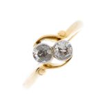 An early 20th century 18ct gold diamond two-stone ring. The old-cut diamond collets, with asymmetric