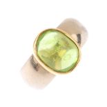 An 18ct gold peridot single-stone ring. Of bi-colour design, the oval peridot cabochon collet,