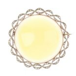 A diamond and gem-set brooch. The circular yellow-green gem cabochon, within a rose-cut diamond