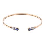 A 9ct gold sapphire and diamond cuff bangle. The pear-shape sapphire collet terminals, with single-