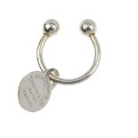 TIFFANY & CO. - a key ring. Designed as a U-shape key ring suspending a circular tag stamped '