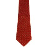 HERMÈS - a silk tie. Featuring a design of yellow linked chainmail on a cherry red background.