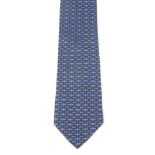 HERMÈS - a silk tie. Featuring a brown rounded 'H' pattern on a blue background. Length measures