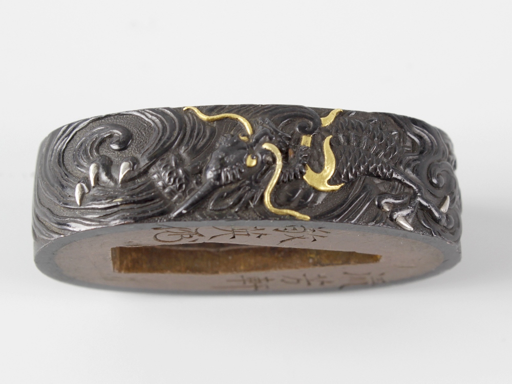 A Japanese bronze fuchi. Probably Meiji period (1868-1912), decorated in relief with two-colour gold