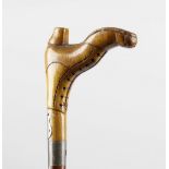 A carved wooden walking cane, the handle modelled as a lady's boot, with applied white metal