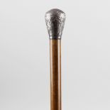 A 19th century white metal handled walking cane, the white metal capped top embossed with scrolls