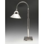 A modern Art Deco style nickel plated lamp raised above a rectangular stepped base, the arm