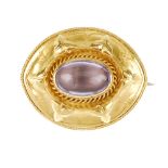 A late 19th century amethyst cabochon brooch. Of oval outline, the central amethyst cabochon with