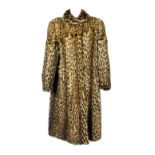 A knee length ocelot coat. Featuring a shawl collar, hook and eye fastenings, balloon sleeves and