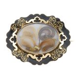 A late Victorian gold enamel memorial brooch. Of scalloped oval outline, the black enamel border