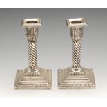 A pair of late Victorian silver mounted candlesticks, each stepped and filled square base rising