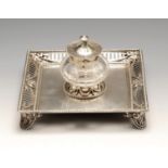 An Edwardian silver inkwell, the square base with raised pierced gallery edge with beaded borders,