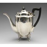 An Edwardian silver hot water pot, of lobed oval form having applied wooden handle and raised upon