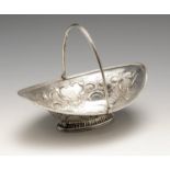 A George III or IV silver sweetmeat basket with swing handle, the oval form embossed with floral and