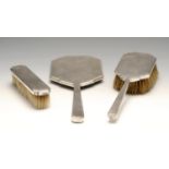 An Art Deco silver mounted three piece dressing table set, including a hand mirror, hairbrush and