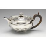 A George III silver teapot, the circular body part fluted, rising to the gadrooned rim and similarly