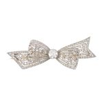 A platinum and 18ct gold diamond bow brooch. The circular-cut diamond, with vari-cut diamond pierced