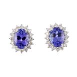 A pair of 18ct gold tanzanite and diamond cluster earrings. Each designed as an oval-shape