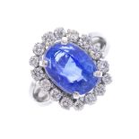 An 18ct gold sapphire and diamond cluster ring. The oval-shape sapphire, with brilliant-cut