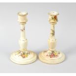 A pair of Royal Worcester candle sticks, each with an ivory blush coloured ground, decorated with