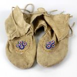 A pair of vintage leather moccasins, with leather ties and beadwork decoration depicting flowers,