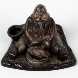 An unusual cold painted cast metal novelty inkwell. Modelled as a portly seated gentleman eating a