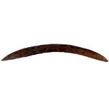 An Australian Aboriginal stone-carved hardwood boomerang. The curved upper face incised with a