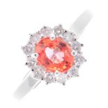 An 18ct gold sapphire and diamond cluster ring. The oval-shape orange sapphire, within a brilliant-