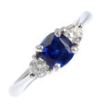 A platinum sapphire and diamond three-stone ring. The cushion-shape sapphire, with brilliant-cut