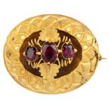 A mid Victorian gold garnet brooch. Comprising three graduated oval-shape garnets and foliate sides,