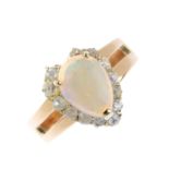 An opal and diamond cluster ring. The pear opal cabochon, within an old-cut diamond surround, with