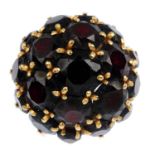 A garnet cluster ring. Designed as a circular-shape garnet bombe, with bar shoulders and tapered