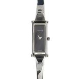 GUCCI - a stainless steel quartz lady's 1500L bangle watch. The plain black dial, with a rectangular