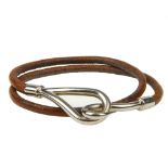 HERMÈS - a bracelet. Designed as a tan leather cord, with silver-tone metal hook terminal to one end