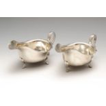 A pair of 1930's silver sauce boats, each of typical plain form with shaped rim and high curved