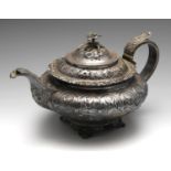 A George IV silver teapot, the compressed circular form embossed and chased throughout with floral