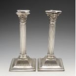 An early twentieth century pair of matched silver mounted candlesticks, the square plinth bases with