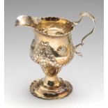 An early George III silver cream jug, the bulbous form to a footed base having scalloped rim and