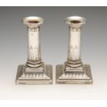 An early twentieth century pair of silver mounted candlesticks, each square plinth base with stiff