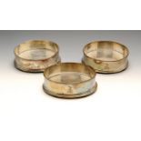 A set of three George III silver mounted bottle coasters, each of circular form with reeded rims,