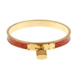 HERMÈS - a Kelly bangle. The circular gold-tone bangle with inlaid tan leather and buckle detail