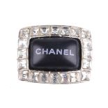CHANEL - a ring. Designed as a black cabochon panel, reading 'Chanel' in white, with surround of