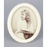 A 19th century carved ivory oval shaped photograph frame, the bevelled glazed central panel within a